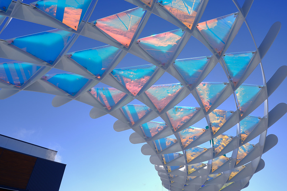 The public art installation, Windward Light, designed by Heavy, Urban Systems, is modeled after a mother bird, protecting everyone under the eight-foot canopy. Located in Calgary, Alberta, this new installation features Goldray Glass’s dichroic glass. 