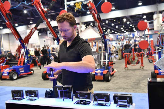 man holding shower enclosure hardware at a trade show