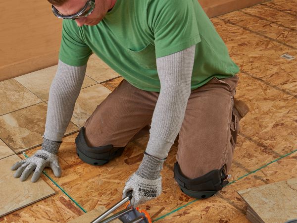 worker with kneepads installs floor