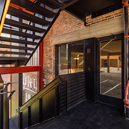 a photo of a stairwell landing outside a brick building that leads to a fire-rated glass entrance system