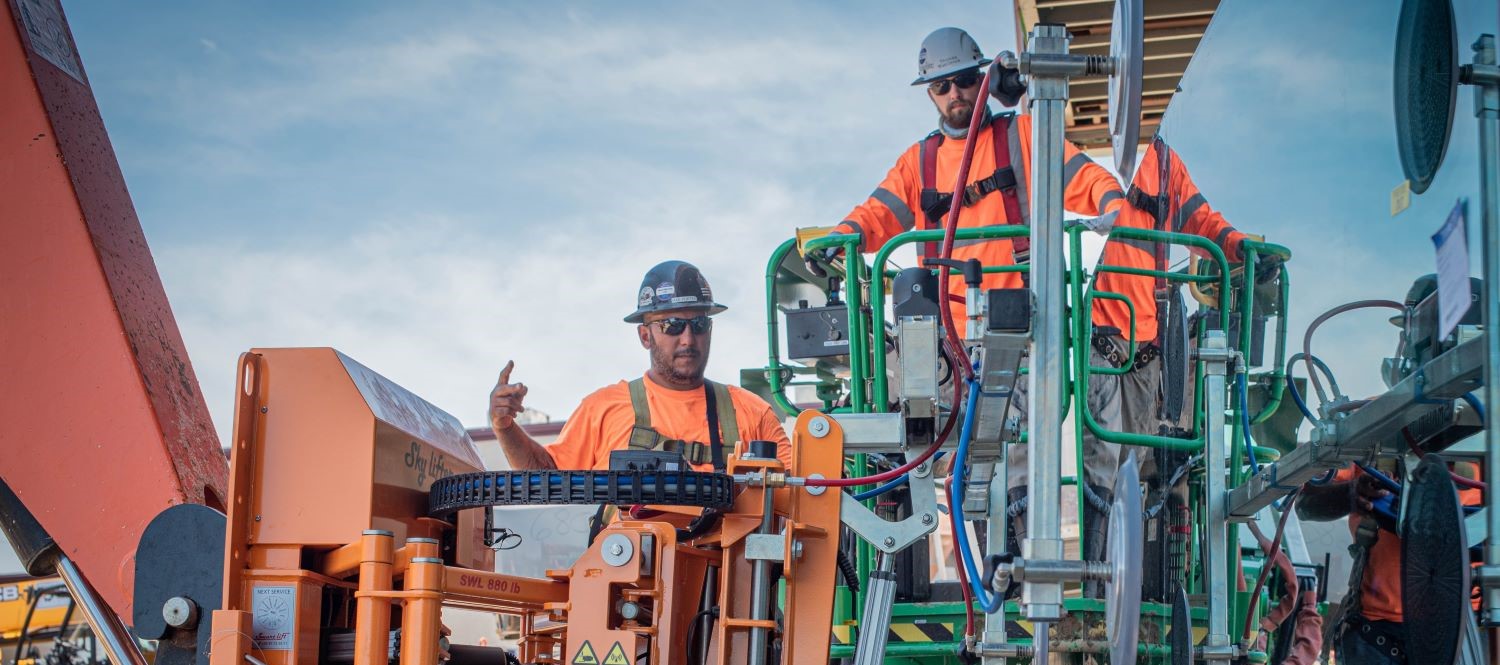 two glaziers on jobsite use glass handling machinery