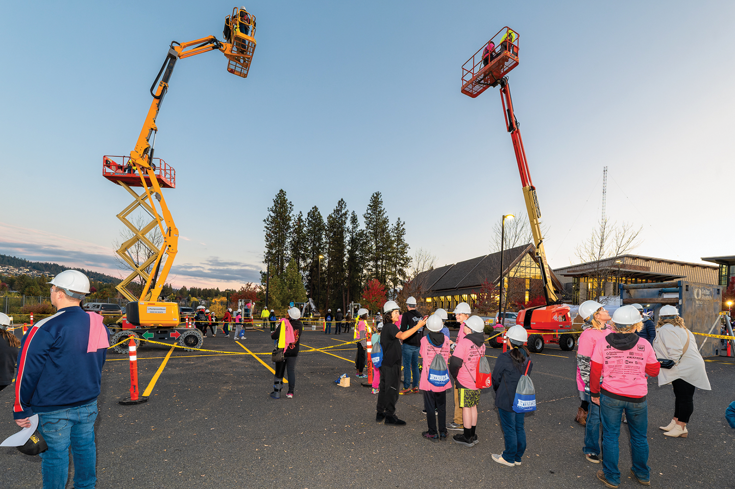two construction cranes amid crowd of students