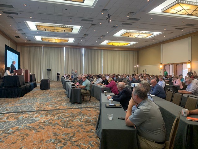 Conference attendees in a general session in hotel conference room. 