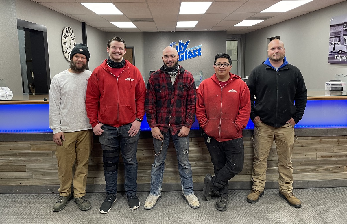 apprentices standing in front of a City Glass sign