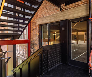 a photo of a stairwell landing outside a brick building that leads to a fire-rated glass entrance system