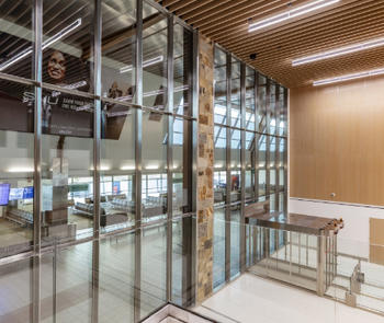 an interior view of a building with a several story glass curtain wall separating one rom from another